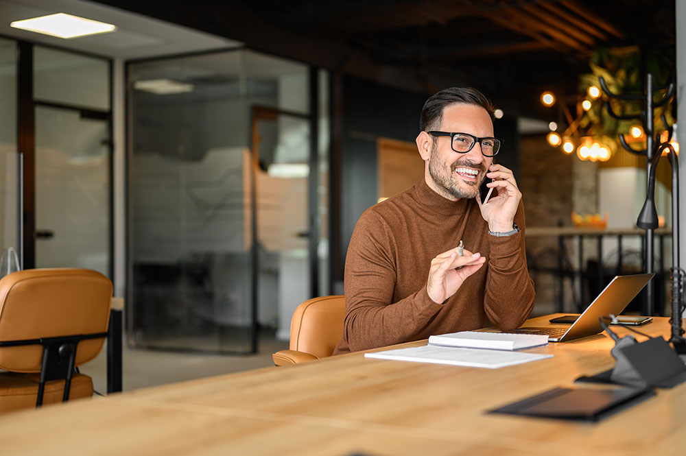 professional man on the phone in front of a laptop