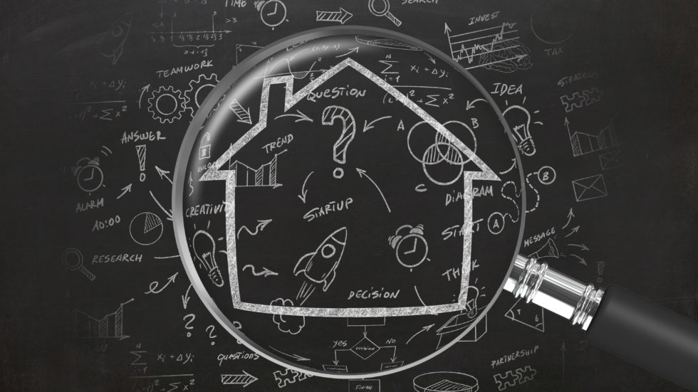 House on chalkboard with magnifying glass